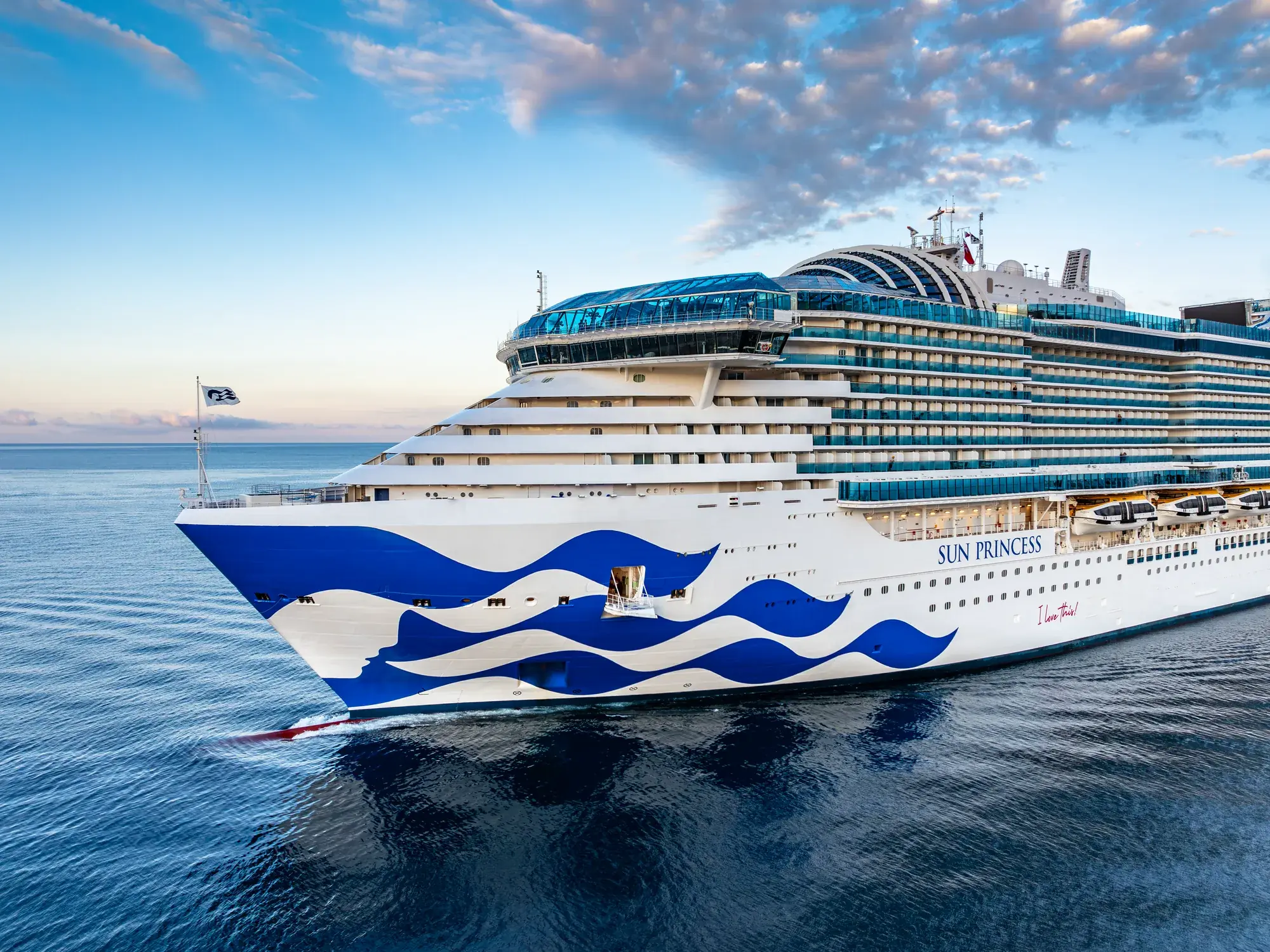 Sun Princess'in gün doğumunda önden görünümü; pruvada Princess deniz kızı logosu