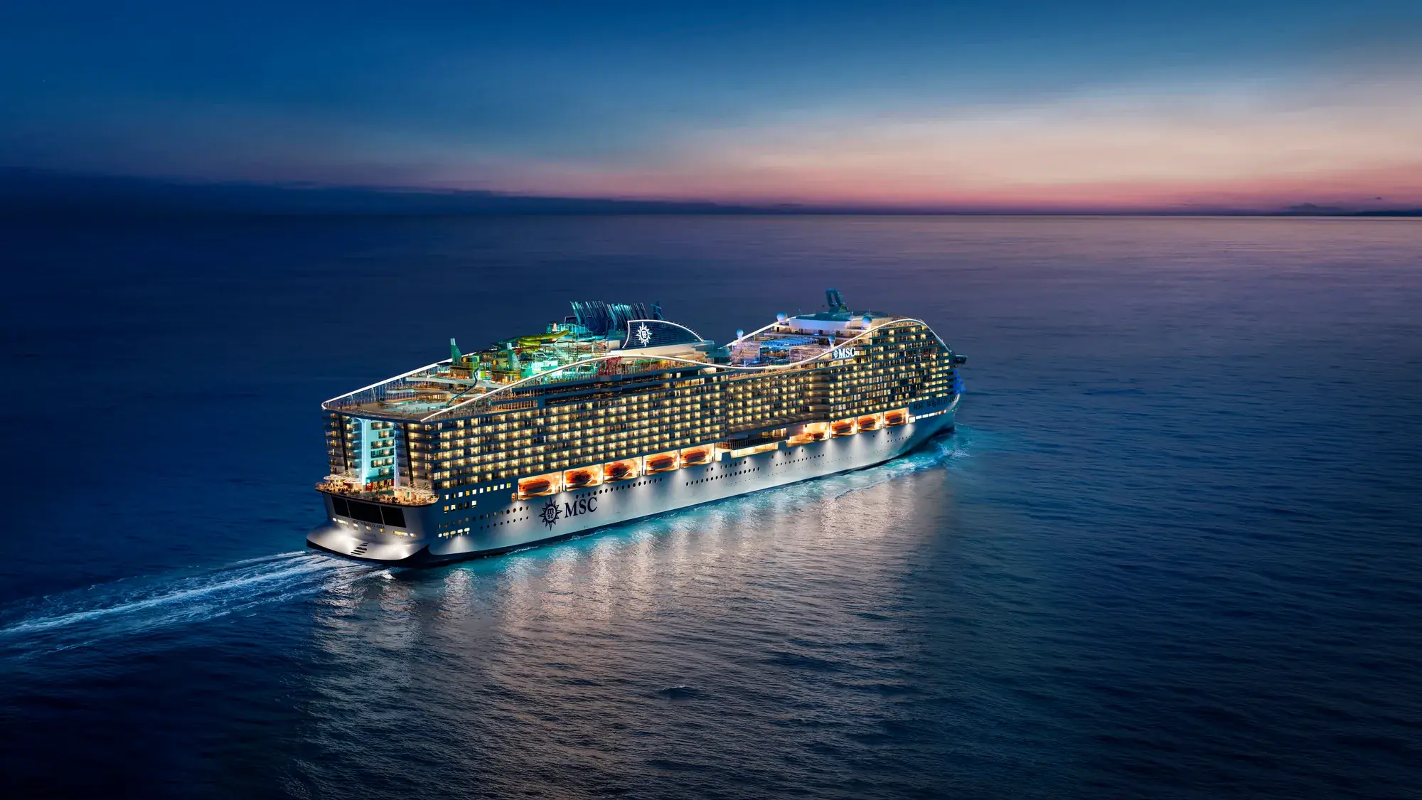 MSC World Asia akşam ışıklarıyla açık denizde seyir halinde, kıç taraftan havadan görünüm (tasarım görseli)