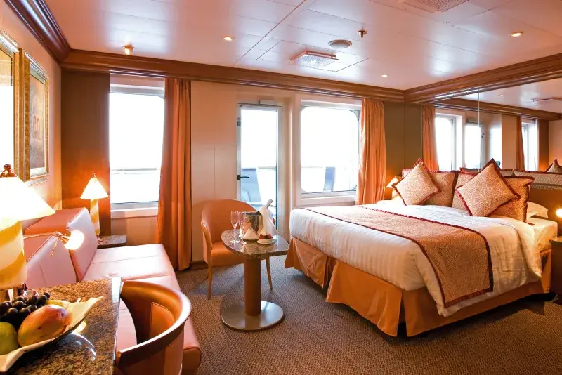 Costa Serena balkonlu suit, yatak ve oturma alanı