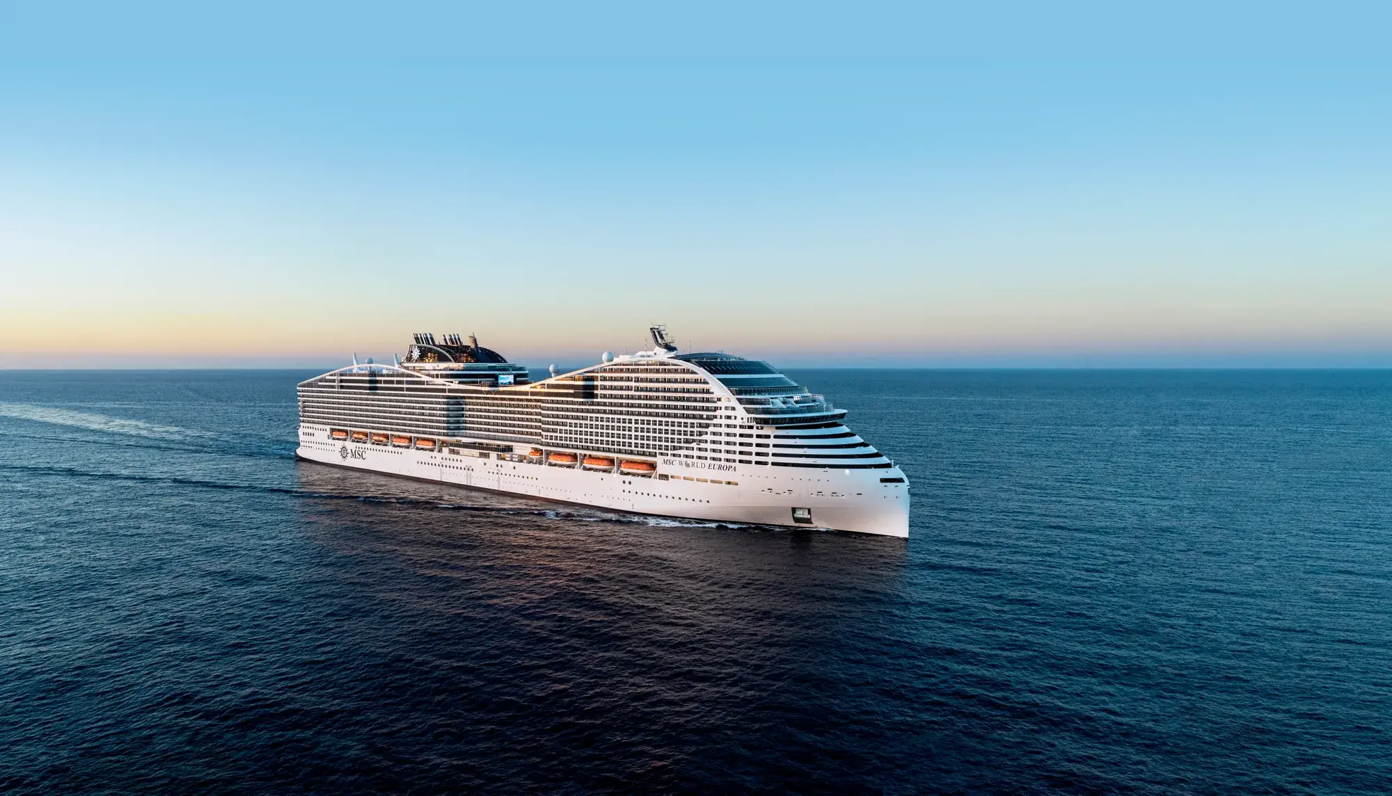 MSC World Europa alacakaranlıkta açık denizde seyir halinde, yandan havadan görünüm