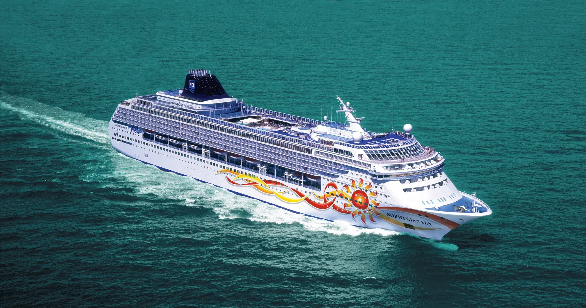 Norwegian Sun'ın açık denizde kuşbakışı görünümü; güneş desenli gövde